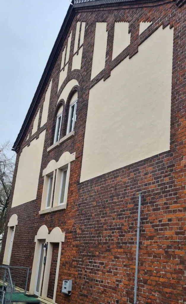 Klinkergiebel mit hellen Putzfeldern und ausgewaschenen, hellen Fugen vor der Sanierung