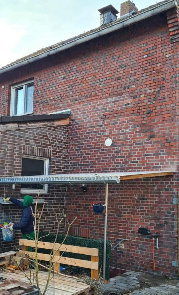 Klinkerhauswand mit Vordach und dunklem Fugenbild vor der Sanierung