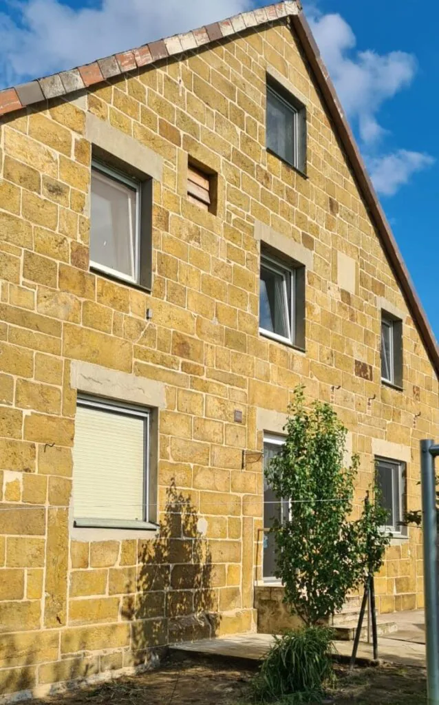 Gereinigter Sandsteingiebel mit hellen Steinflächen und weißen Fensterrahmen