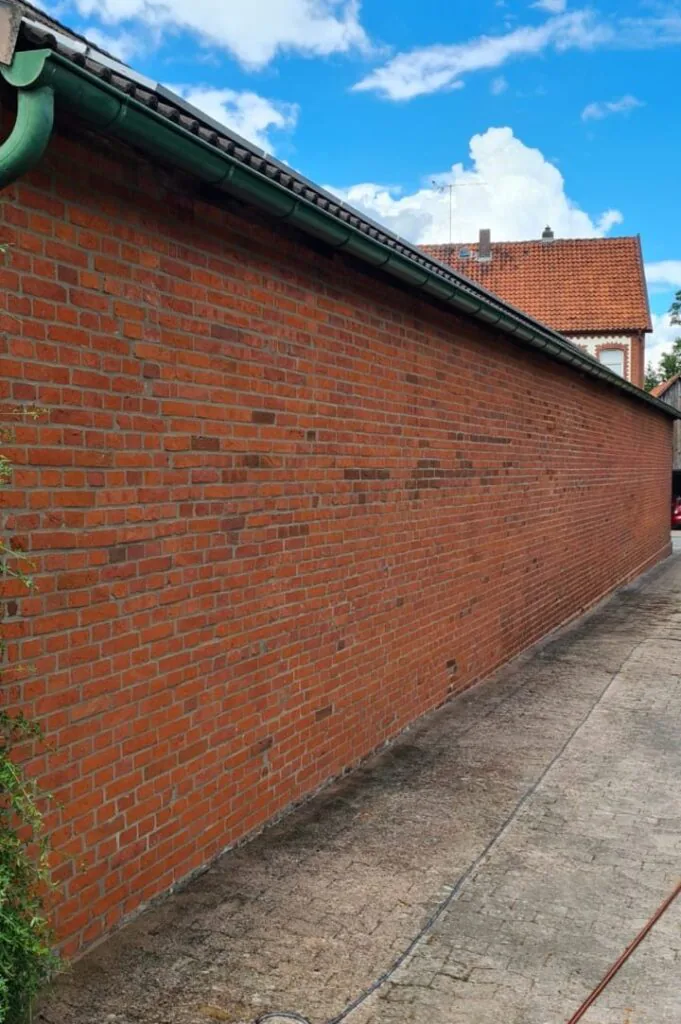 Lange Klinkerwand nach der Sanierung mit sichtbaren roten Steinen und gleichmäßigen Fugen